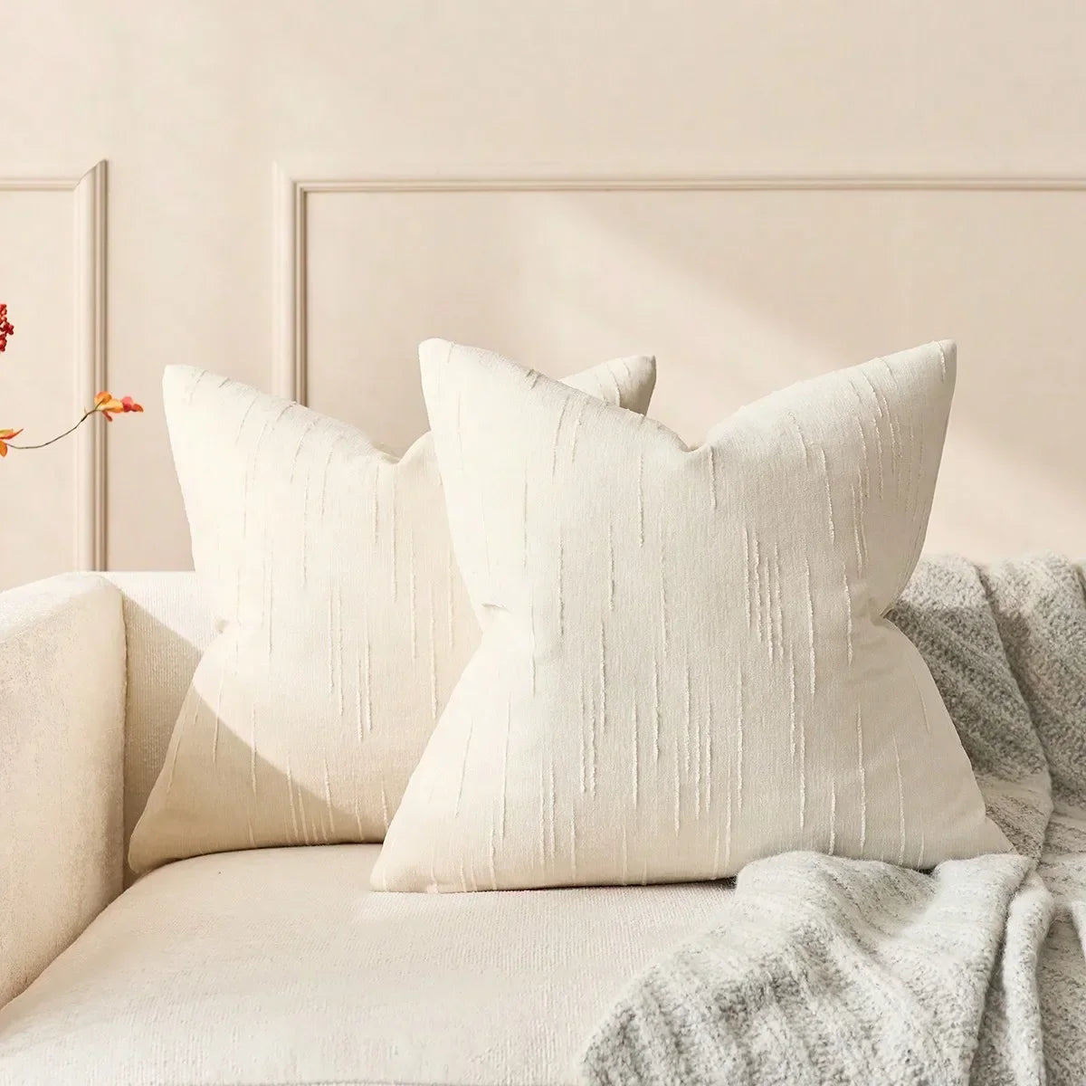 Housse de coussin en lin imitation, beige, motif géométrique bohème Nesty, deux housses de coussin carrées beige à texture rayée verticale, posées sur canapé devant mur à moulures