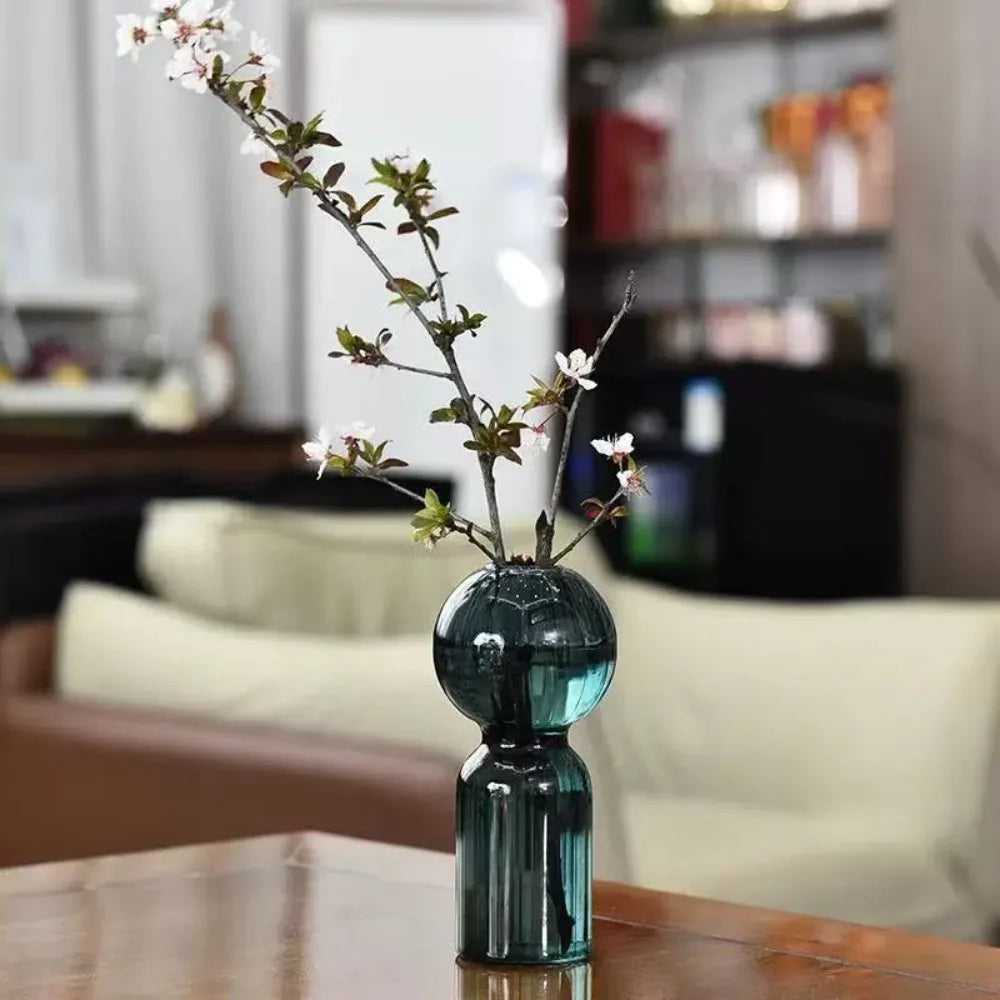 Vase en verre strié coloré, esprit scandinave Nesty, vase bleu canard forme boule garni d'une branche de fleurs de cerisier, sur table en bois