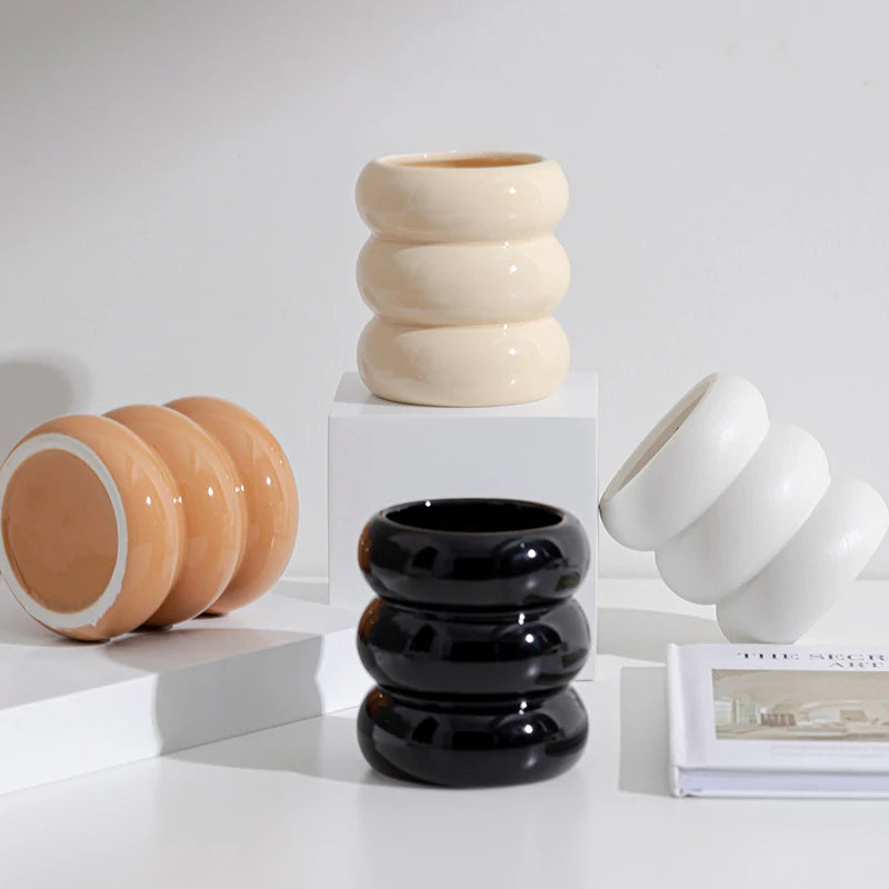 Bougeoir cylindrique en céramique blanche Nesty - Trois bougeoirs empilés en anneaux, coloris crème, noir et blanc, posés près d'un livre