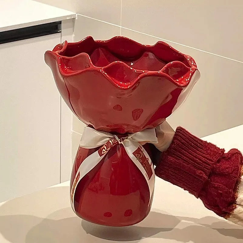 Vase en céramique en forme de rose, modèle bureau Nesty, vase céramique rouge à col évasé ondulé, noué d'un ruban blanc, tenu par une main en pull rouge