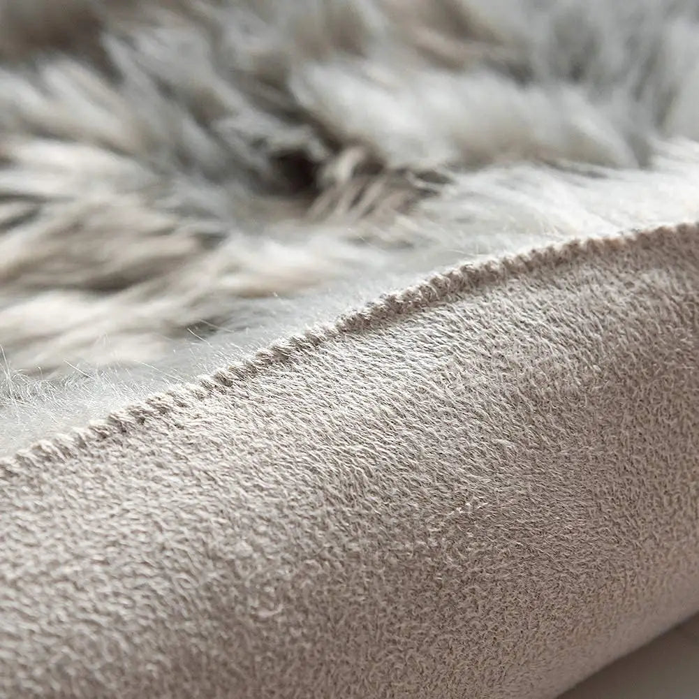 Gros plan sur la fourrure grise épaisse du tapis et son envers en suédine beige cousue.