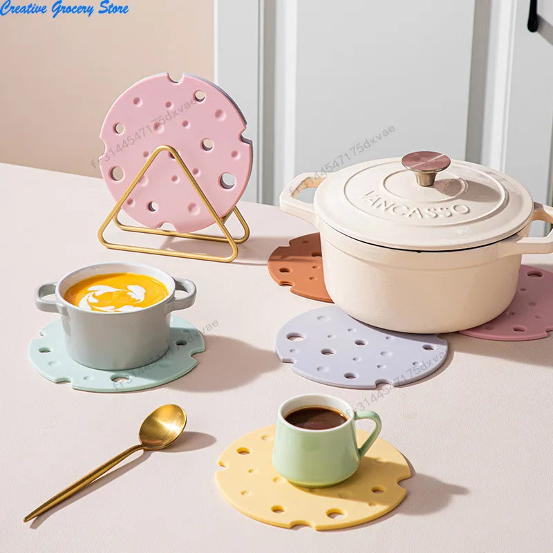Dessous de plat en silicone forme fromage, plusieurs coloris, sous une cocotte, une soupière et une tasse de café - Nesty