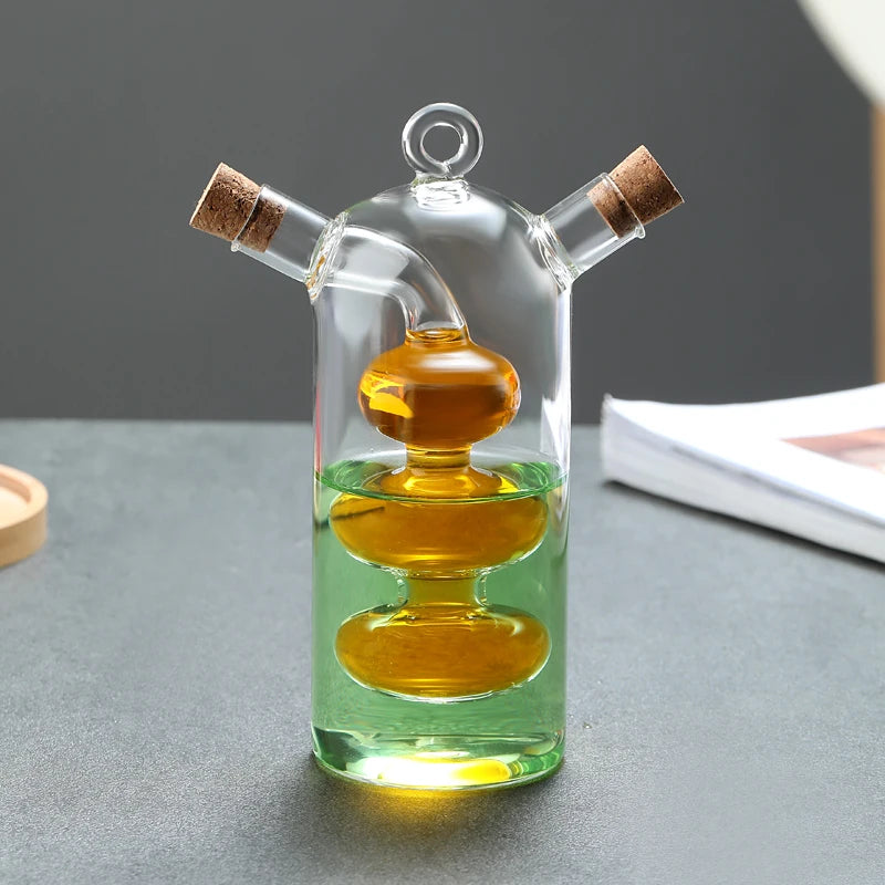 Flacon à sauce double compartiment en verre Nesty, flacon en verre à deux compartiments avec bouchons en liège, rempli de sauce foncée et d'huile dorée à motif ondulé, sur table sombre