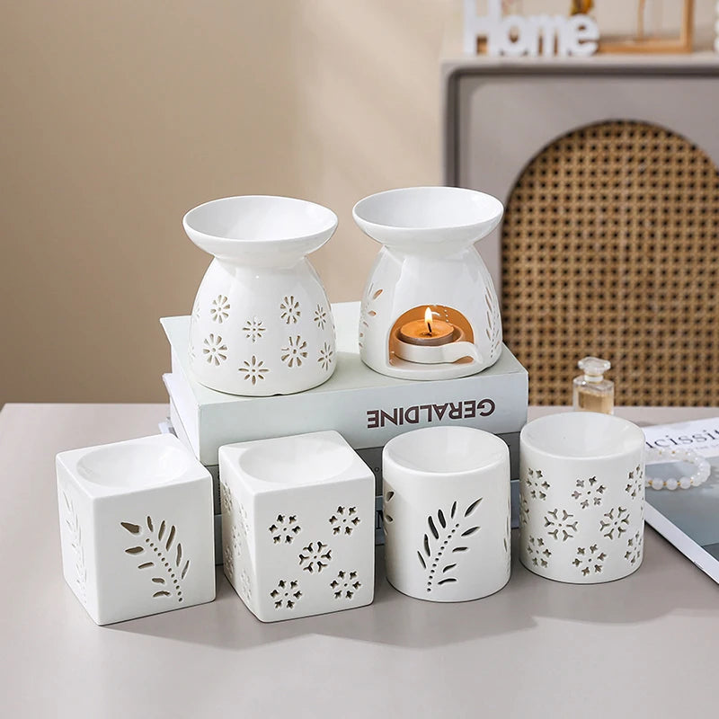 Brûle-parfum en céramique ajourée Nesty - Assortiment de formes avec un modèle allumé, près d'un flacon de parfum