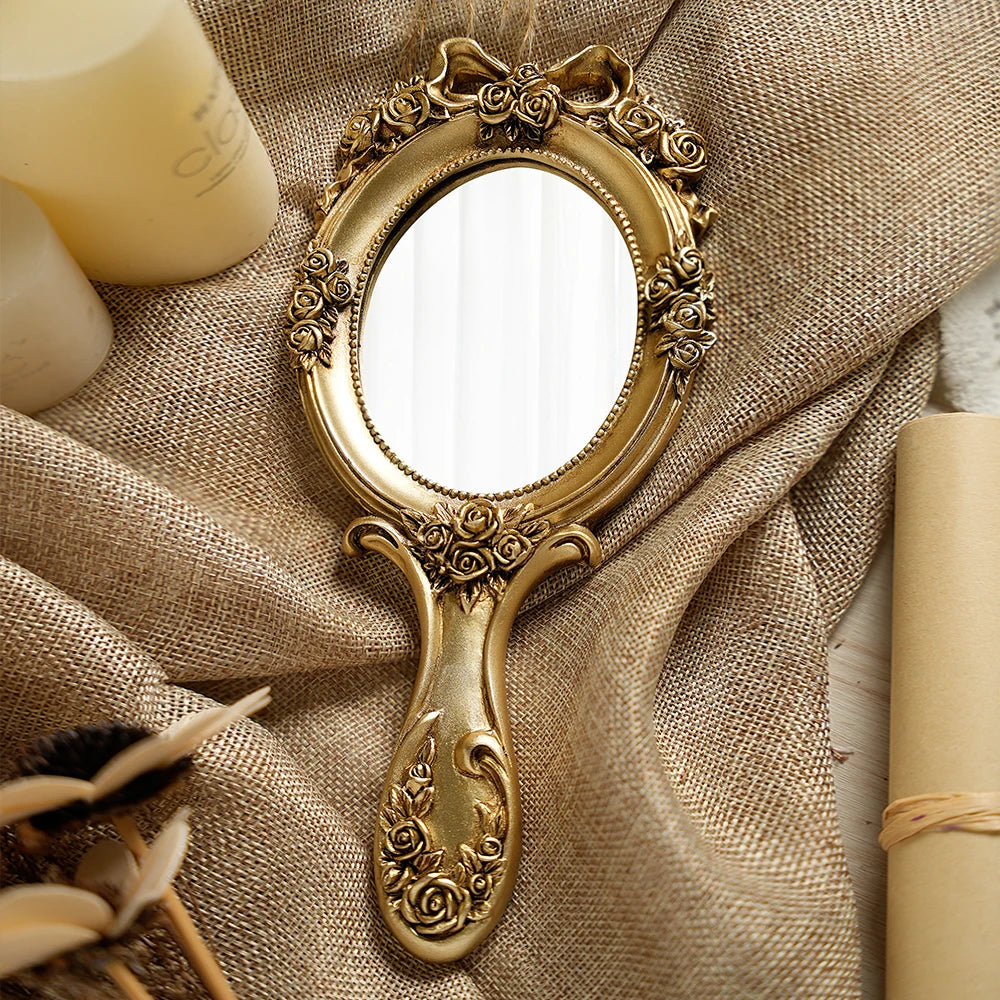 Miroir à main baroque Nesty - Modèle doré en gros plan sur toile de jute, avec bougies