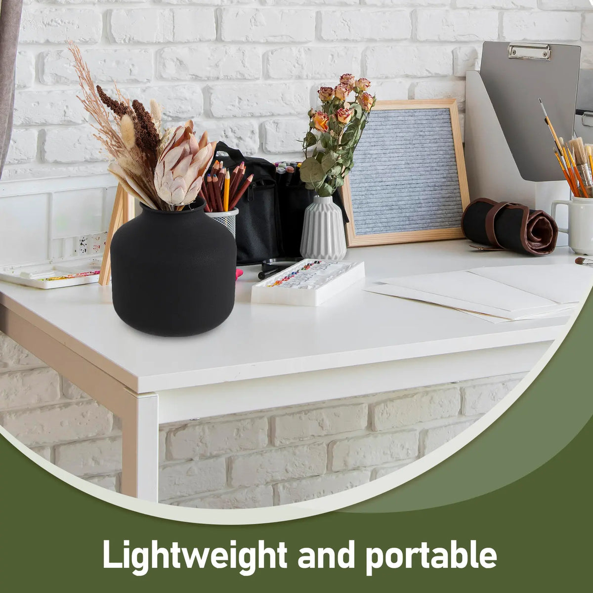 Vase en métal noir mat, style minimaliste Nesty, garni de fleurs séchées, sur bureau d'artiste avec palette de peinture et pinceaux