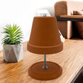 Chauffe-plat en terre cuite Nesty - Lampe chauffe-plat en pot de terre cuite renversé sur pied métallique, posée sur une table en bois avec une plante