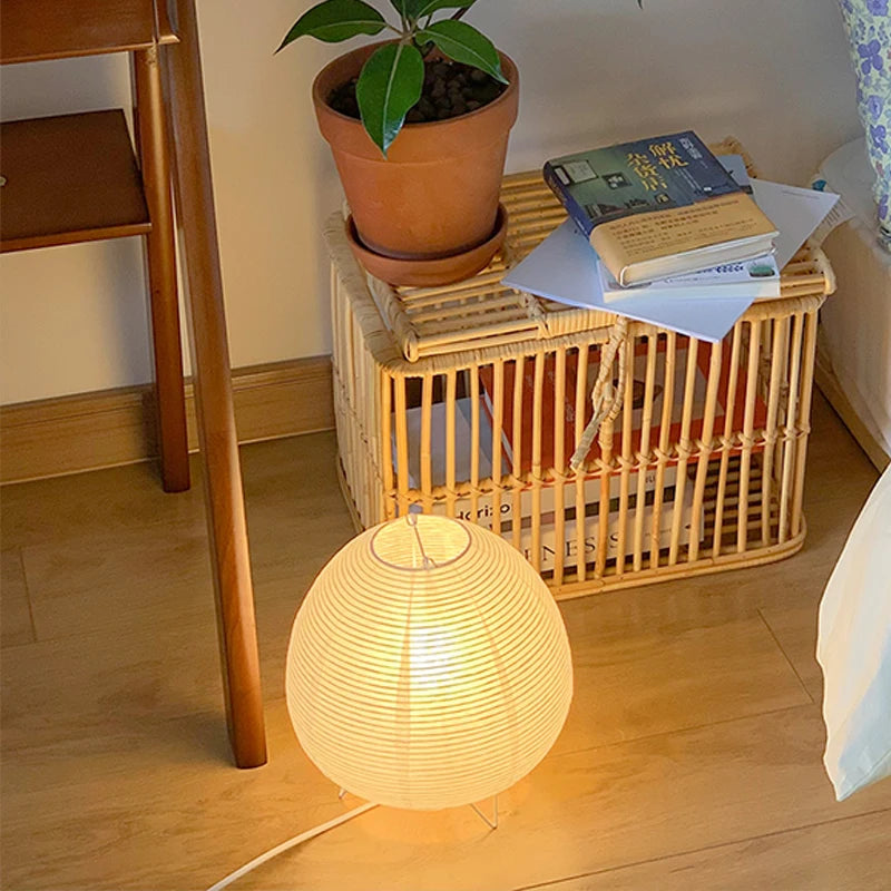 Lampe de table nordique Nesty - Allumée au sol près d'un coffre en rotin