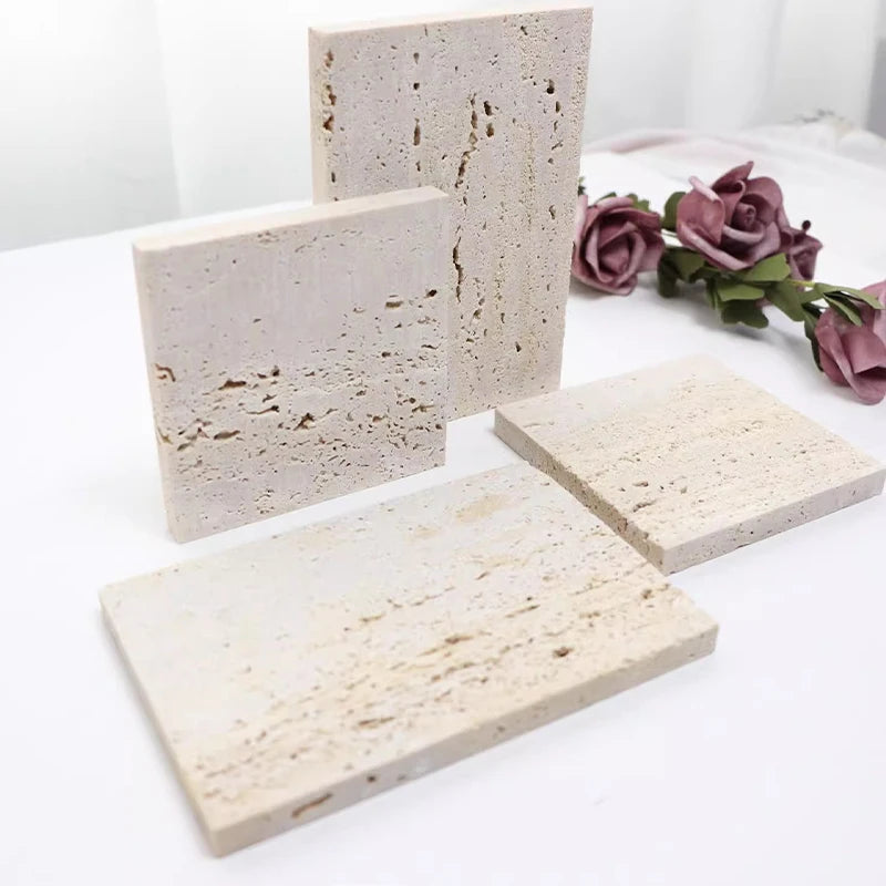 Vide-poche en travertin Nesty - Quatre plaques de tailles différentes posées sur une table blanche avec roses séchées