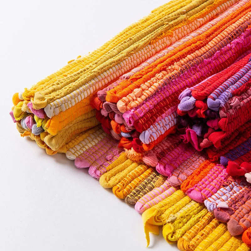 Tapis à franges tissé main — motif rayé - Nesty, gros plan sur des rouleaux de tapis chiffon aux coloris variés (jaune, orange, rose, rouge)