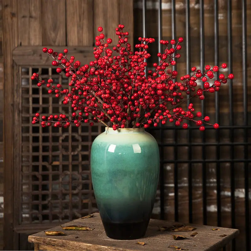Grand vase en céramique, style rétro pour fleurs séchées Nesty, vase en céramique émaillée turquoise et noir garni de branches de baies rouges, sur table en bois devant claustra