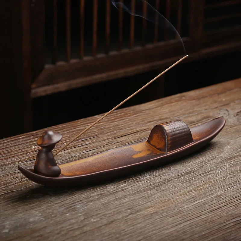 Plateau brûle-encens en céramique Nesty - Forme de barque avec figurine, bâtonnet d'encens allumé sur table en bois