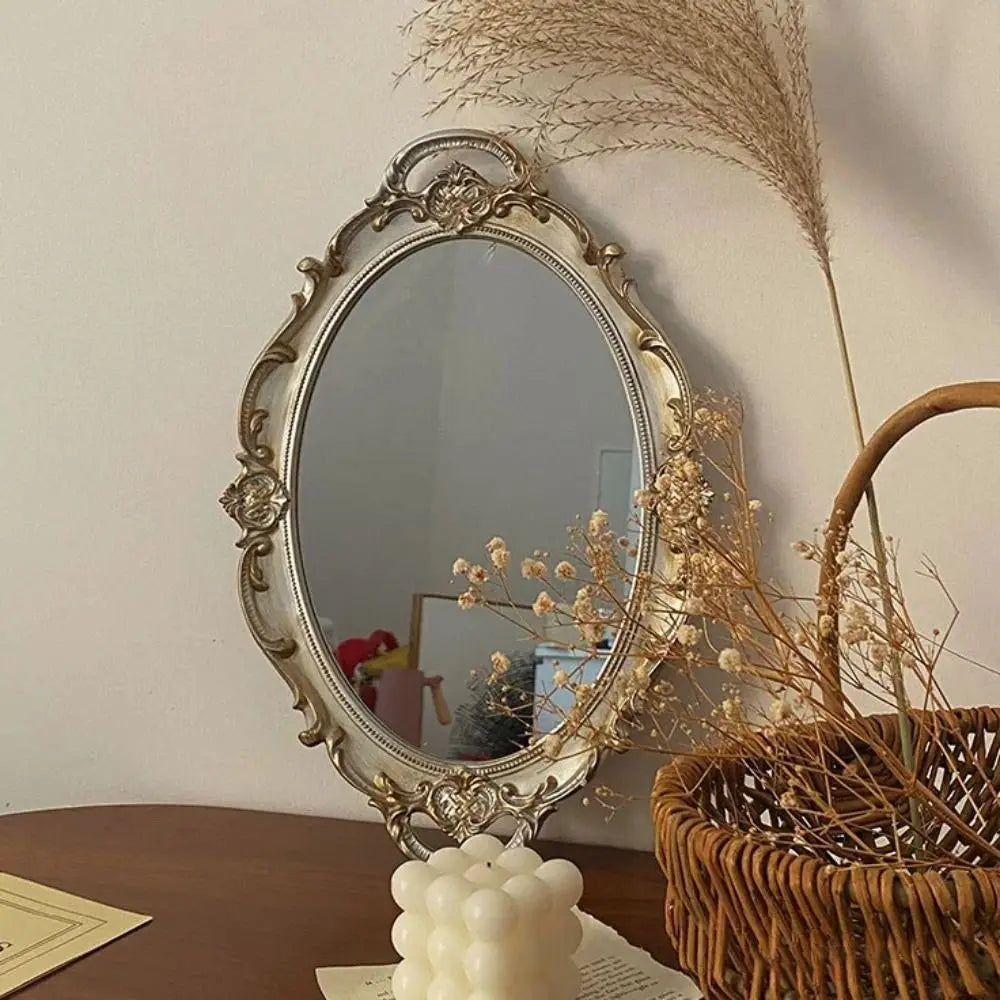 Miroir ovale à cadre baroque argenté, posé debout sur une bougie ronde, avec panier en osier et fleurs séchées - Nesty