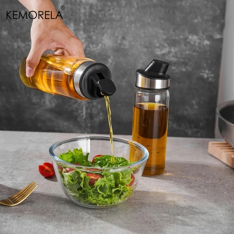 Burette à huile en verre à fermeture automatique Nesty, main versant de l'huile dans un bol de salade, seconde burette remplie de sauce foncée à côté
