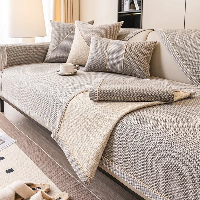 Housse de canapé en lin tissé, antidérapante, toutes saisons Nesty, canapé beige recouvert d'une housse tissée à motif chevrons, avec trois coussins assortis et bordure contrastante beige, tasse posée dessus