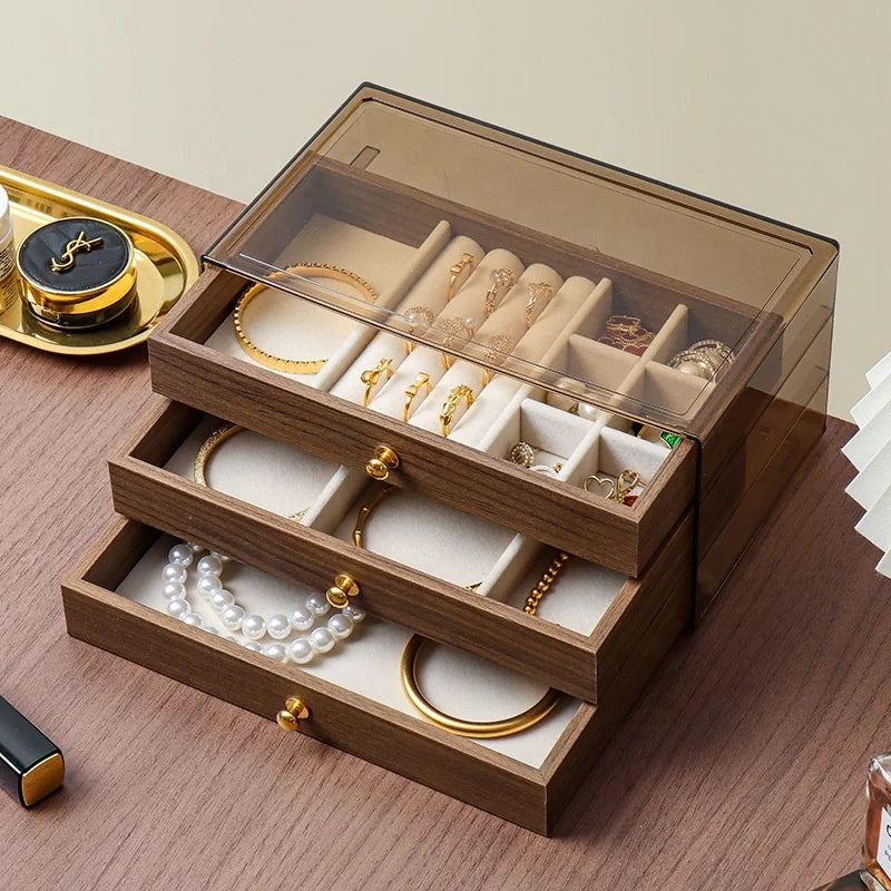 Boîte à bijoux en bois à tiroirs Nesty - Tiroirs ouverts avec bracelets dorés, collier de perles et bagues, sur table en bois