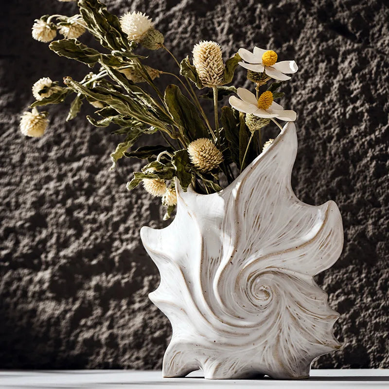 Vase en céramique blanche forme coquillage Nesty - Avec fleurs séchées immortelles et marguerites, devant un mur en pierre texturée