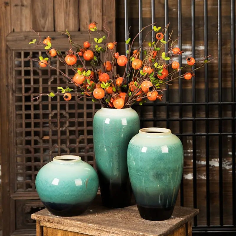Grand vase en céramique, style rétro pour fleurs séchées Nesty, mêmes trois vases émaillés turquoise et noir garnis de branches de baies oranges, sur table en bois devant claustra