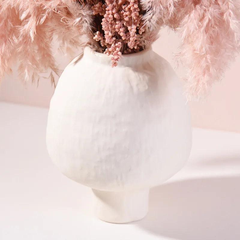 Vase en poterie fait main, grain brut, esprit artisanal Nesty, gros plan sur le col et la panse texturée d'un vase blanc garni de pampas et fleurs séchées roses