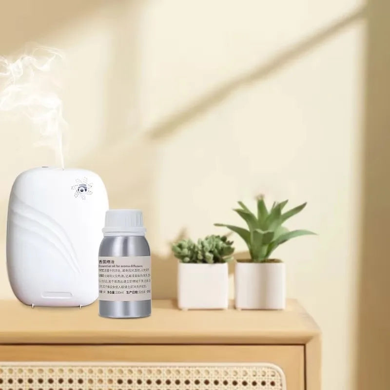 Recharge huile parfumée pour diffuseur Nesty - Flacon argenté à côté d'un diffuseur blanc avec vapeur, entouré de succulentes