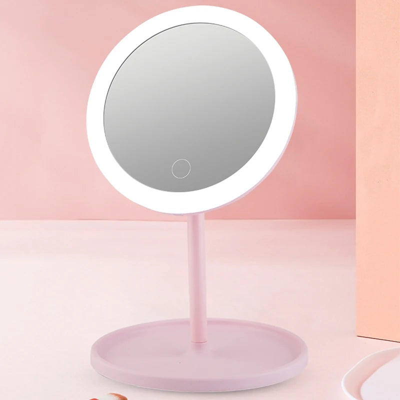 Miroir de voyage rond avec anneau lumineux LED et plateau intégré, coloris rose pastel, sur fond rose - Nesty