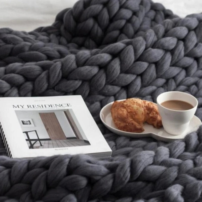 Plaid épais tricoté main, grosses mailles, laine chénille Nesty, plaid en grosses mailles gris anthracite avec livre "My Residence" et plateau croissant-café posés dessus