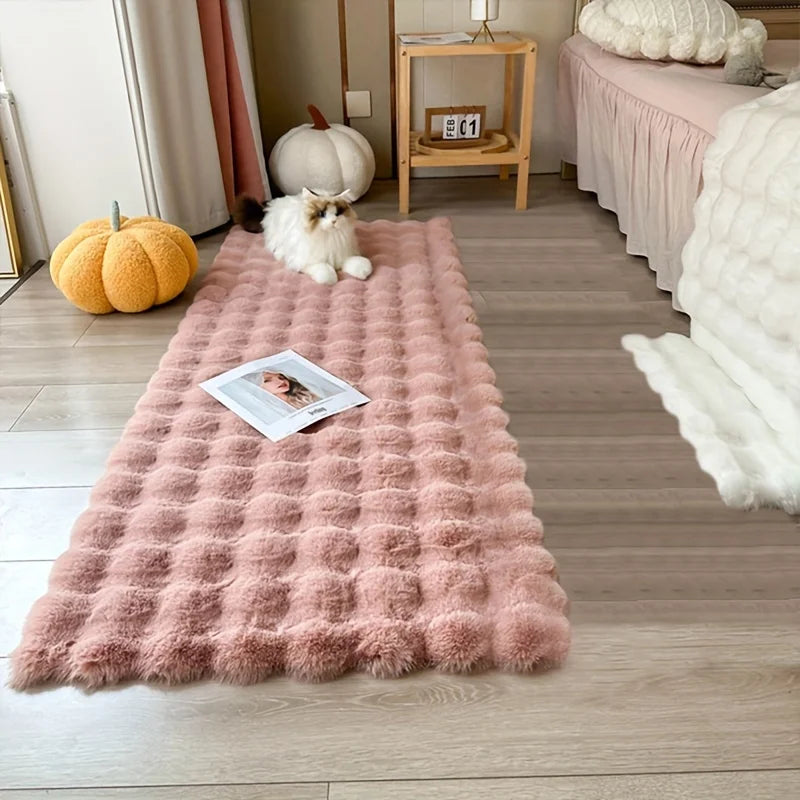 Tapis en fausse fourrure douce — coloris unis - Nesty, coloris rose à texture alvéolée au pied d'un lit avec un chat allongé dessus