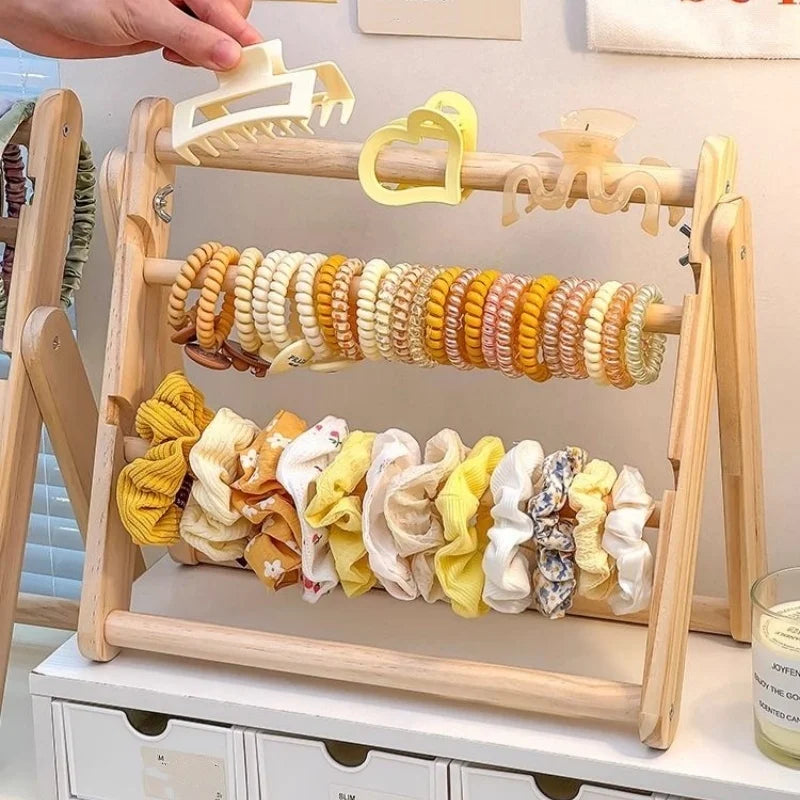 Présentoir en bois pour boucles d'oreilles et bijoux Nesty - Gros plan sur les pinces, élastiques et chouchous jaunes, main ajustant une pince