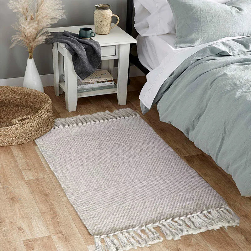 Tapis en coton et lin à rayures — style nordique - Nesty, coloris gris clair chevrons à franges, au pied d'un lit