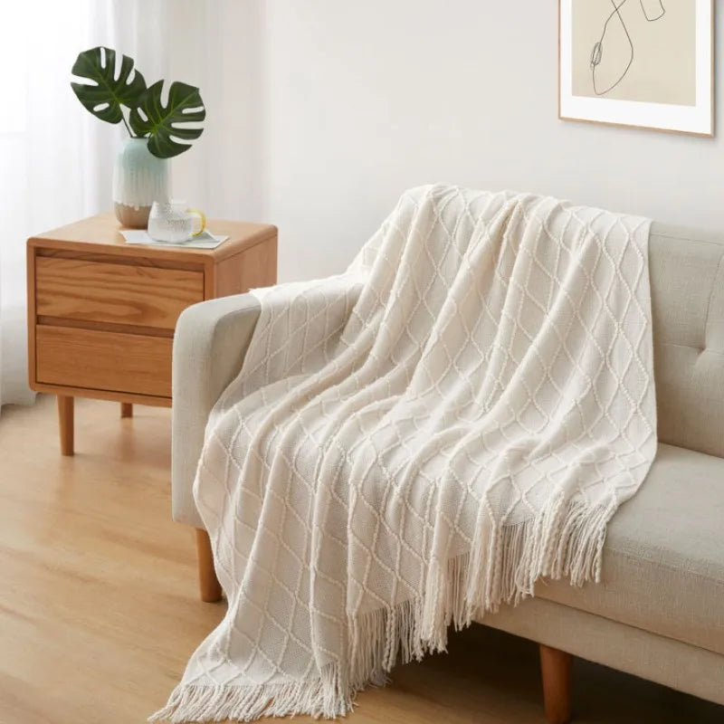 Plaid tricoté bohème blanc cassé Nesty - Drapé sur canapé beige, motif losanges et franges, dans salon lumineux