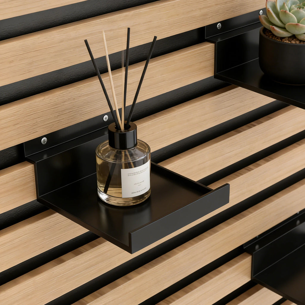 Étagère à clipser pour panneaux acoustiques Nesty, gros plan sur une étagère noire à clipser sur un panneau mural en bois à lattes, diffuseur de parfum et plante grasse posés dessus