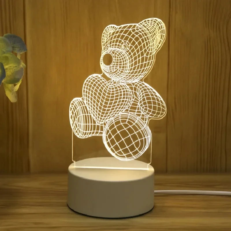 Veilleuse LED ours en acrylique Nesty - Allumée sur une table en bois, fleur à côté