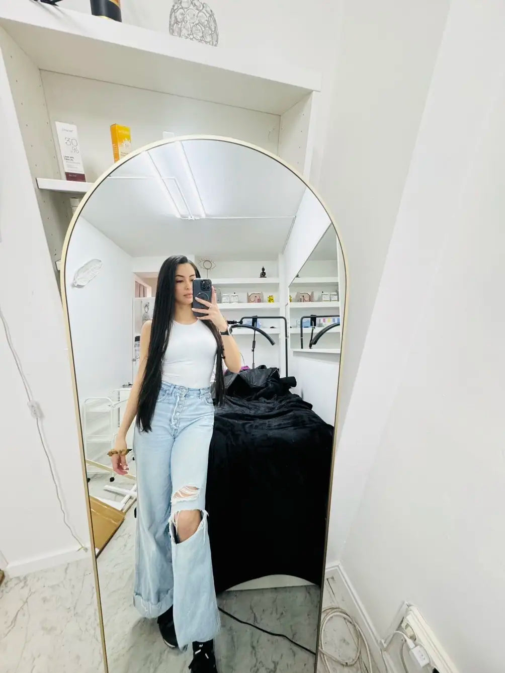 Miroir psyché cintré Nesty - Cadre doré, femme prenant un selfie en jean déchiré et débardeur blanc