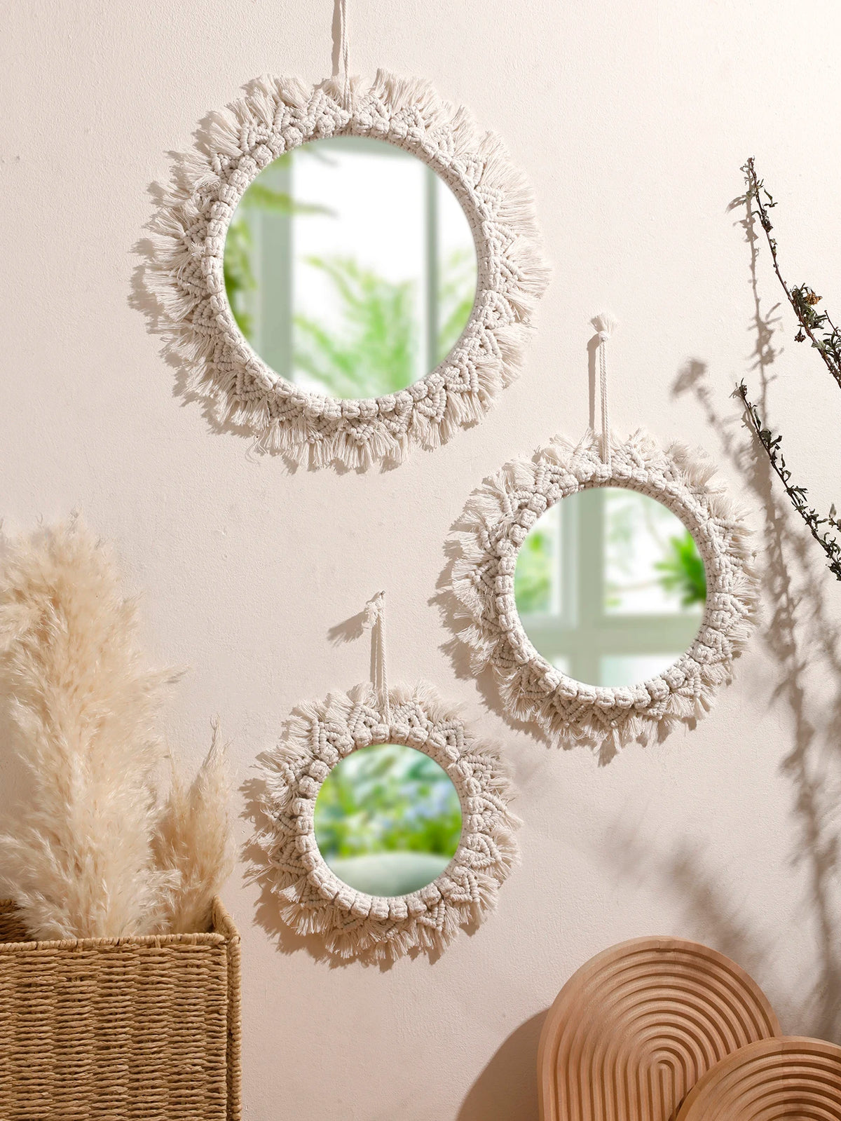 Trois miroirs muraux ronds macramé à franges, tailles décroissantes, suspendus sur mur beige avec pampas et branchages - Nesty