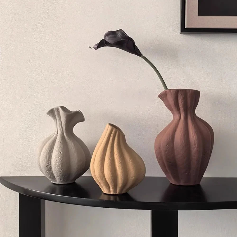 Vase en céramique irrégulier, esprit wabi-sabi, fait main Nesty, trois formes cannelées, gris clair, camel et bordeaux, sur console noire, le grand bordeaux garni d'une fleur de callas noire