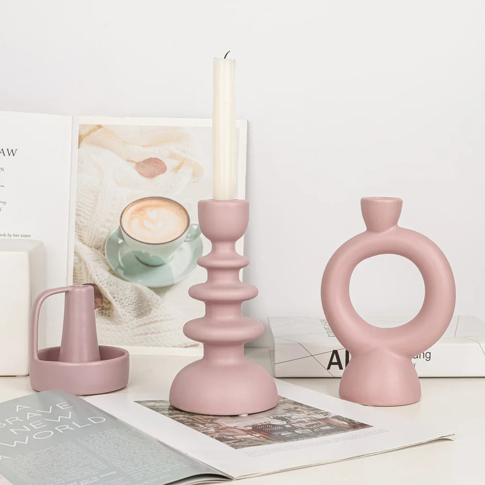 Bougeoir céramique rose poudré galbé torsadé avec bougie allumée, à côté d'un bougeoir en anneau et petit pichet, sur bureau - Nesty
