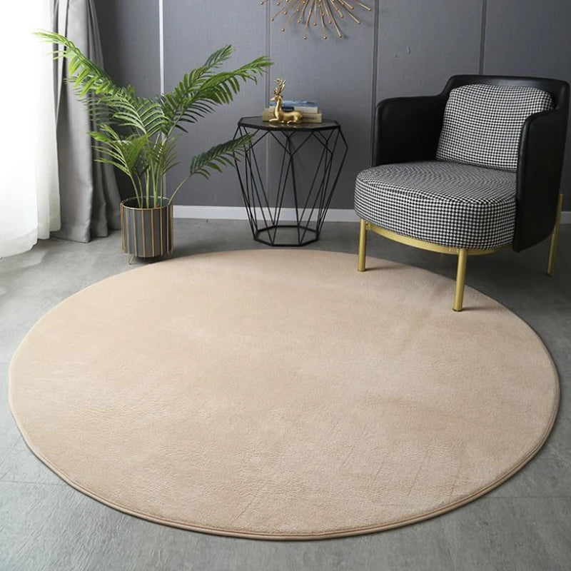 Tapis rond en velours beige, posé au sol dans un salon devant un fauteuil noir à motif pied-de-poule.