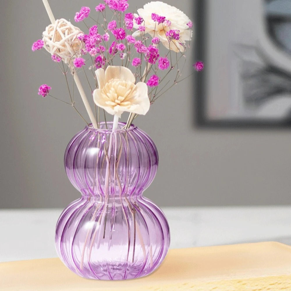 Vase en verre forme calebasse, rayures verticales - Nesty - Coloris violet en gros plan avec fleurs stabilisées roses, fond flou gris