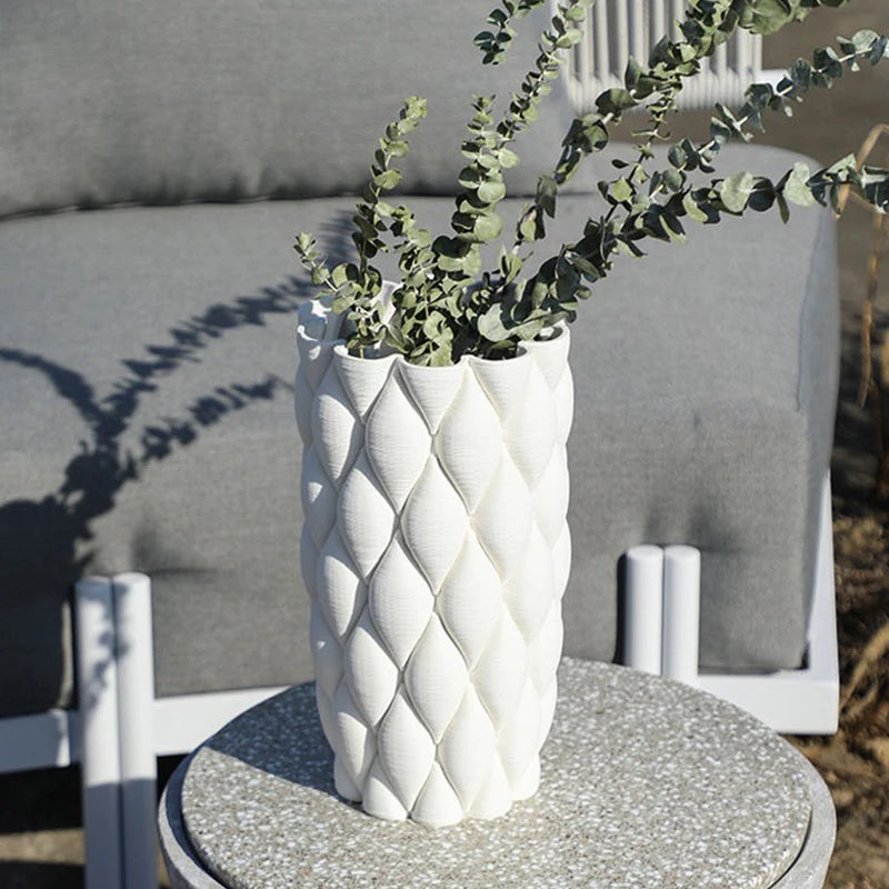 Vase en poterie, pour fleurs séchées ou culture hydroponique Nesty, vase blanc à relief en écailles garni de branches d'eucalyptus, posé sur table d'extérieur devant fauteuils gris