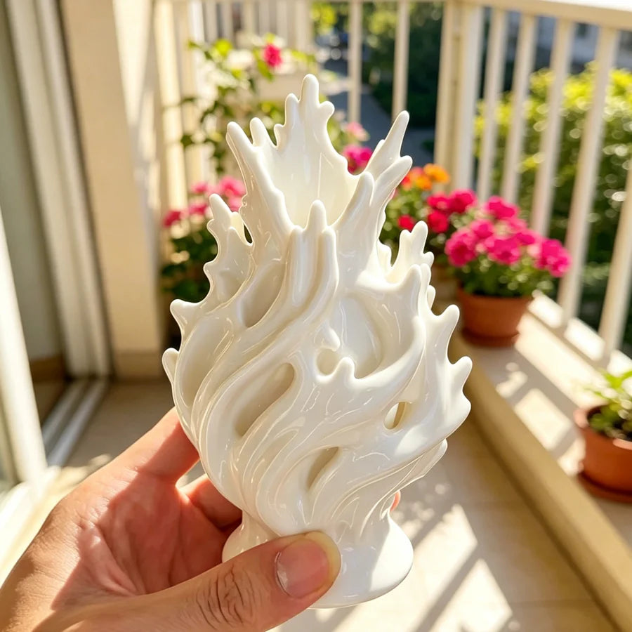 Vase en plastique léger, format table à manger Nesty, forme blanche ajourée en flamme tenue en main, sur un balcon garni de fleurs roses