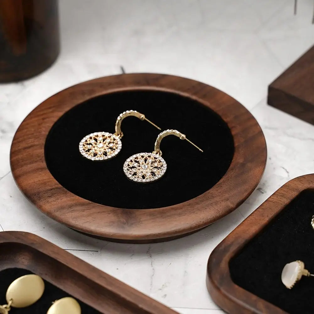 Plateau à bijoux en bois Nesty - Gros plan sur le plateau rond à velours noir avec boucles d'oreilles dorées filigranées