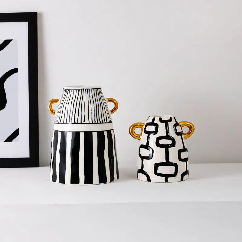 Vase en céramique rayé — silhouette abstraite haute - Nesty - Deux tailles à rayures noir et blanc avec anses dorées, sur étagère près d'un cadre graphique
