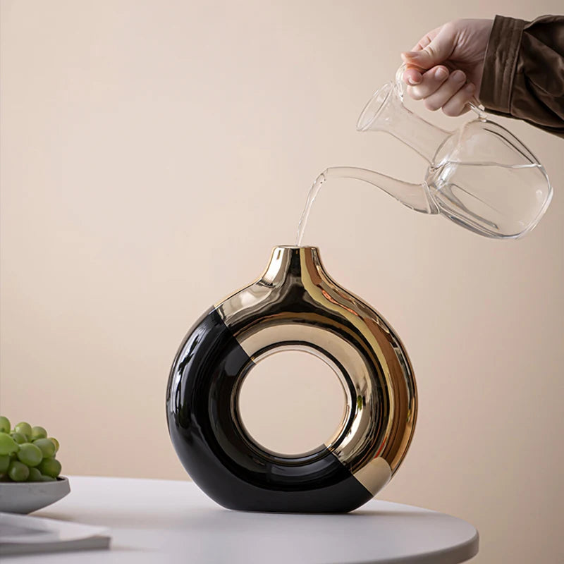 Vase en céramique doré, silhouette nordique, plusieurs tailles Nesty, vase rond ajouré bicolore noir et doré, eau versée depuis une carafe en verre