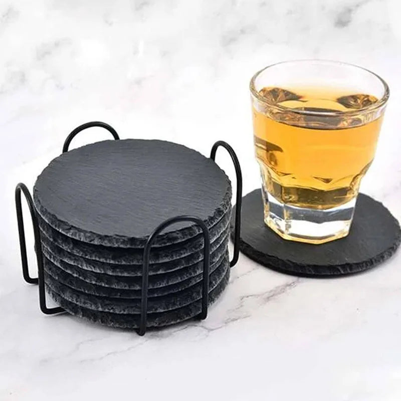 Dessous de verre en ardoise noire ronds sur support métal, avec verre de whisky posé dessus, sur plan en marbre - Nesty