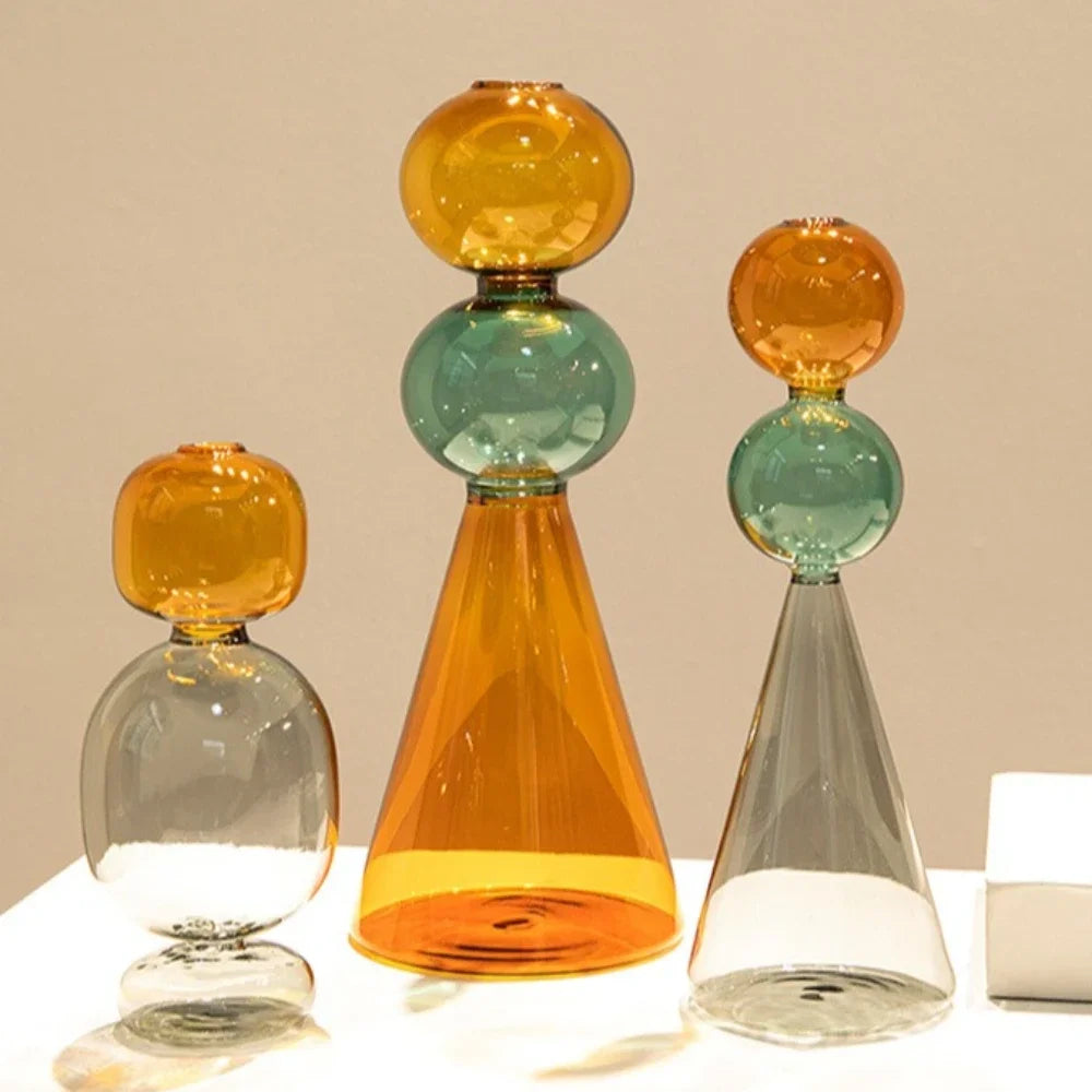 Vase en verre double paroi coloré, culture hydroponique - Nesty - Trois tailles empilées ambré-vert, ambré-gris et ambré-gris seul, sur une table beige