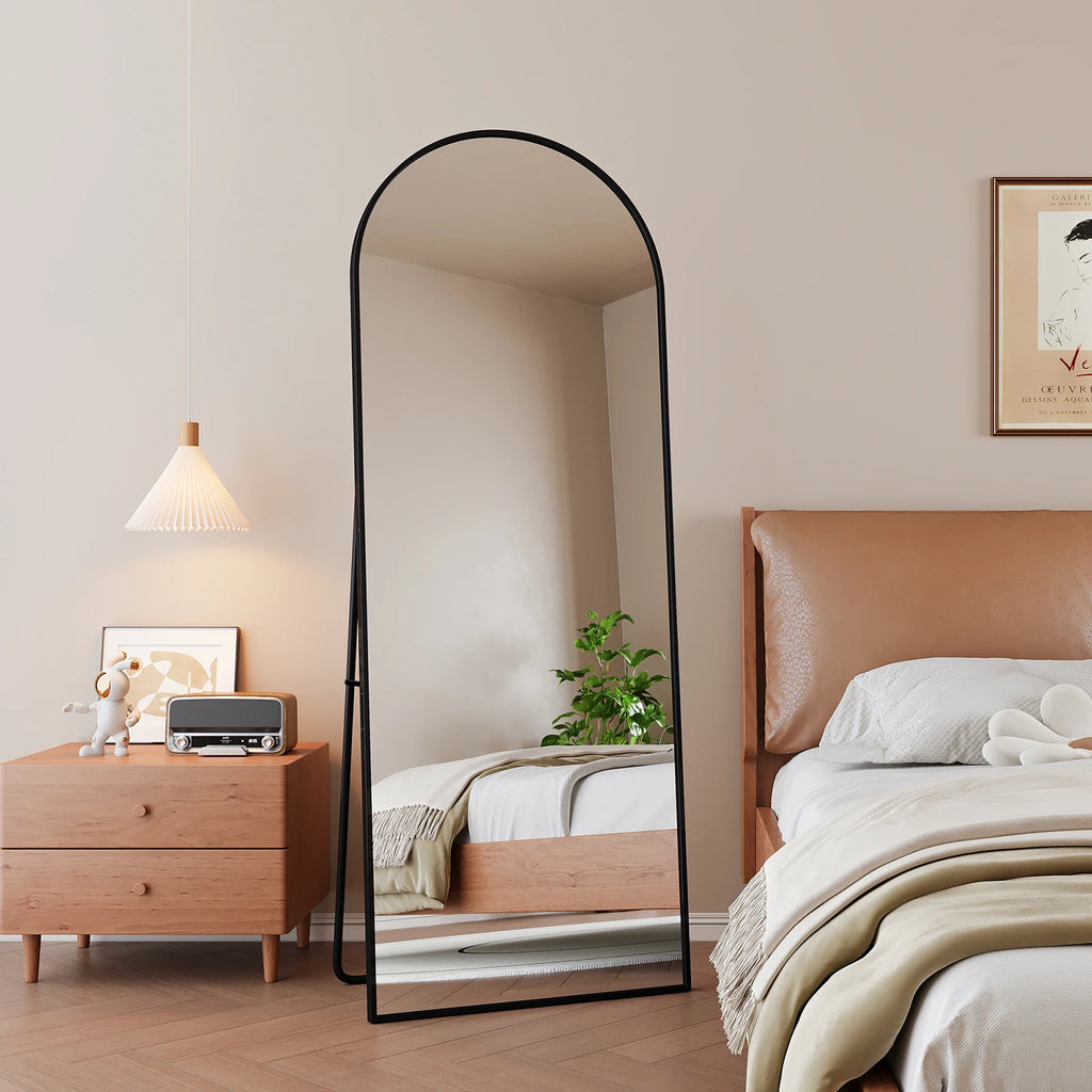 Miroir psyché cintré Nesty - Cadre noir près d'un lit à tête de lit en cuir, reflet d'une suspension et d'une plante