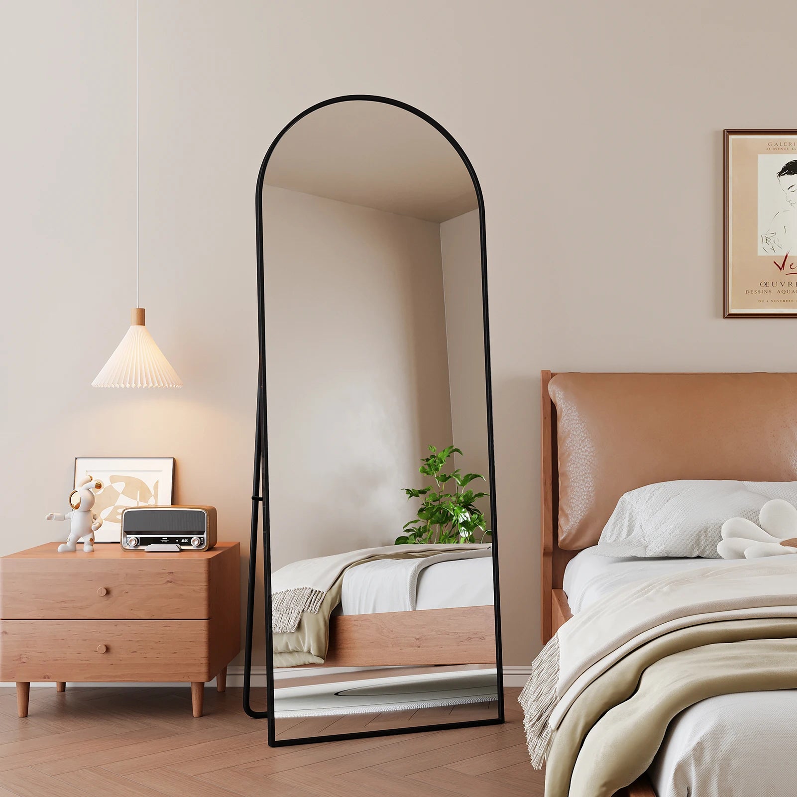 Miroir psyché cintré Nesty - Cadre noir près d'un lit à tête de lit en cuir, reflet d'une suspension et d'une plante