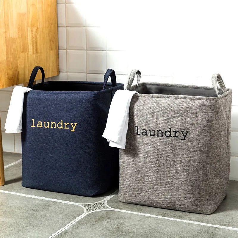 Panier à linge pliable en toile de jute Nesty - Deux coloris bleu marine et gris, inscription laundry, dans salle de bain carrelée
