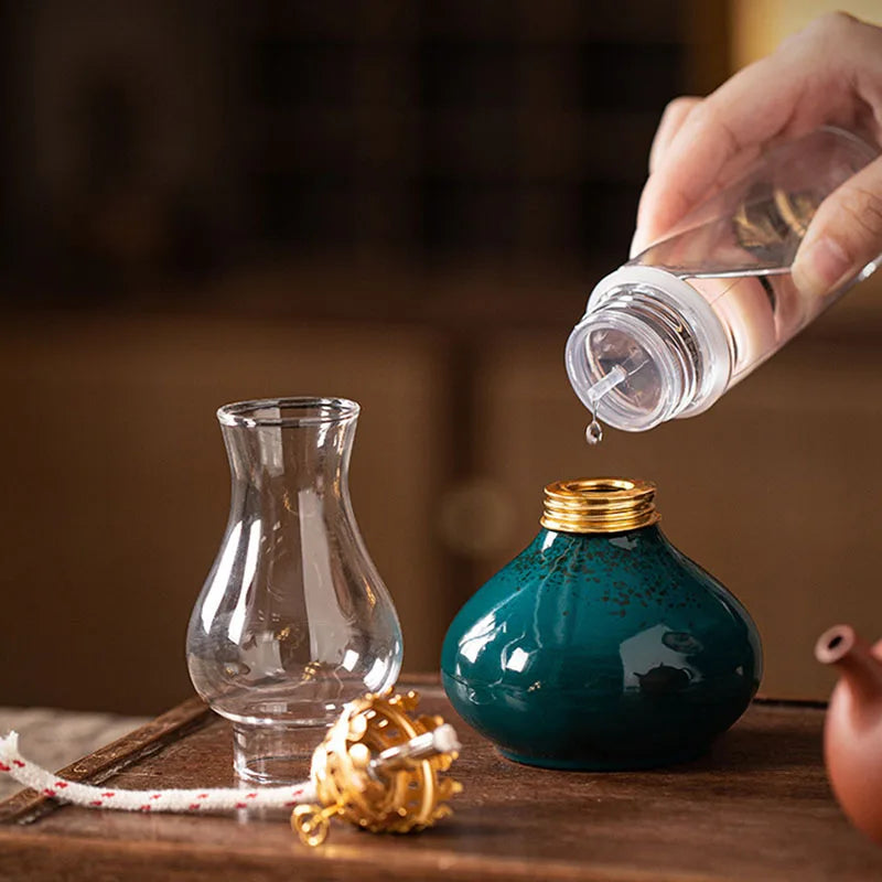 Lampe à huile en céramique Nesty - Remplissage de la lampe verte à l'aide d'un flacon compte-gouttes, cheminée en verre posée à côté