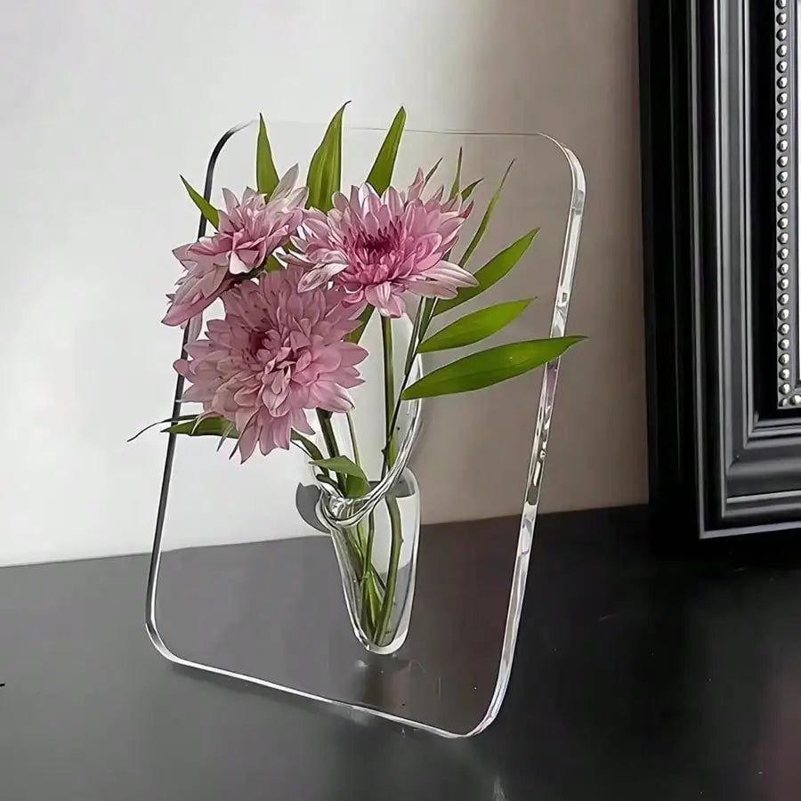 Vase cadre en acrylique transparent Nesty - Chrysanthèmes roses, posé devant un cadre noir